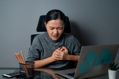 Young woman using mobile phone while sitting on table