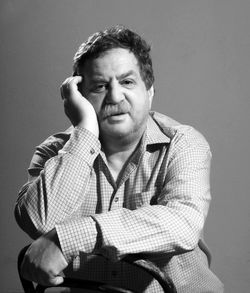 Portrait of mature man sitting on chair against wall