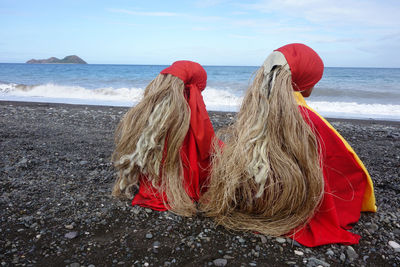 Rear view of women wearing traditional clothing while sitting at beach