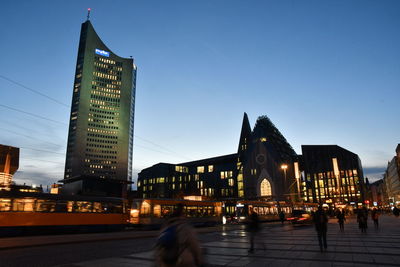 Illuminated city buildings against sky at dusk