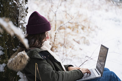 Rear view of woman using mobile phone in winter