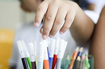 Hands picking up crayons to draw on paper. 