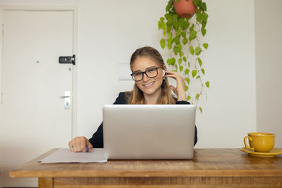 Woman working at home with laptop and papers on desk and headphones. home office . gray notebook 