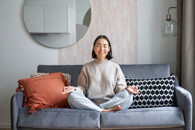 Portrait of young woman sitting on sofa at home