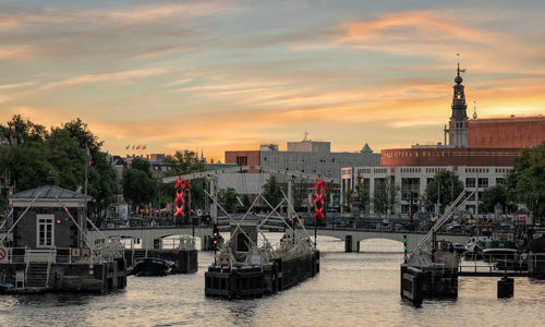 Bridge over river with buildings in background during sunset