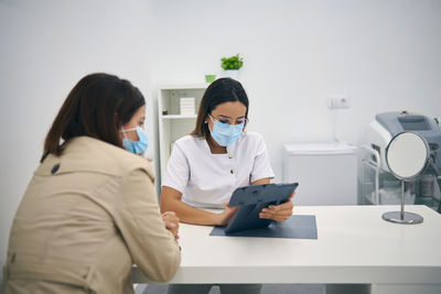 Woman holding camera while standing in front of people