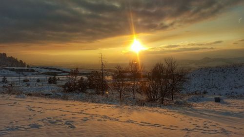 Scenic view of snow covered landscape against sunset sky
