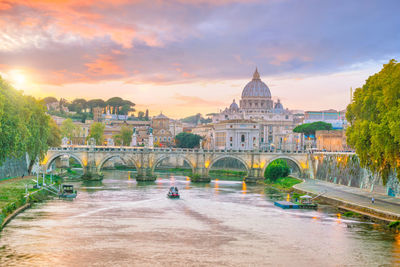 Arch bridge over buildings against sky during sunset