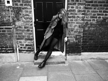 Full length of young woman leaning on door