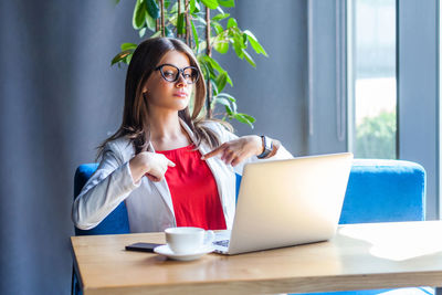 Young woman using phone while sitting on table