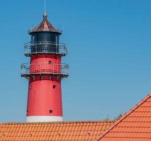 Low angle view of lighthouse against building against clear blue sky