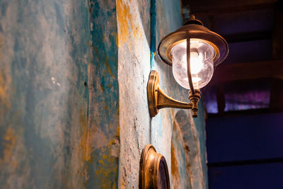 Low angle view of illuminated lamp on wall