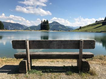 Bench by lake against sky - austria alps