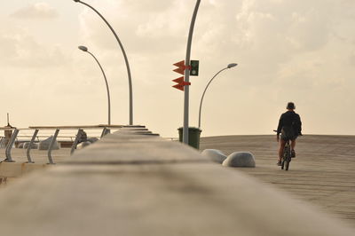 Rear view of a man bicycling on road against sky