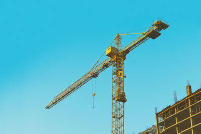 Low angle view of crane against clear blue sky