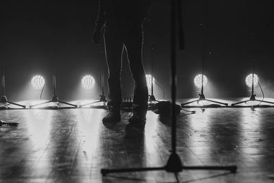 Low section of man standing on illuminated stage