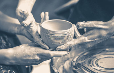 Old vintage photo. a raw clay pot in the hands of a potter. workshop in the pottery workshop