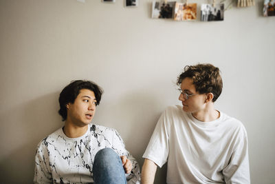 Portrait of a young man sitting on wall at home