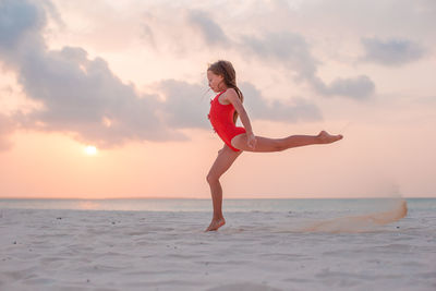 Full length of woman on beach against sky during sunset