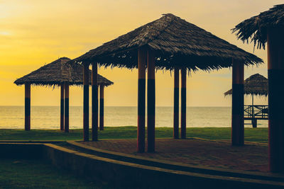 Built structure on beach against sky during sunset