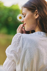 Side view of young woman blowing flowers