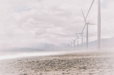 Wind turbines on landscape against sky