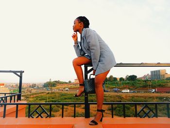 Woman with railing against clear sky