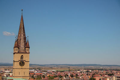 Tower amidst buildings against blue sky