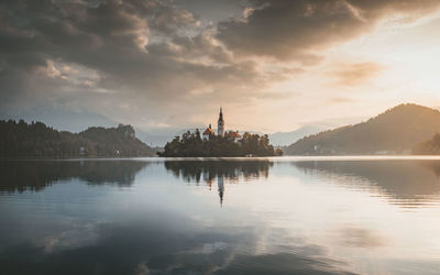 Scenic view of lake against cloudy sky during sunset