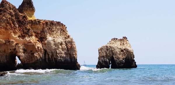 Rock formation in sea against clear sky