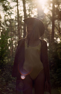 Midsection of woman standing by trees in forest