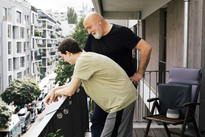 Father talking with son leaning on railing in balcony