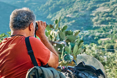 On the road.tourist man traveling on motorcycle,stopped for looking through binoculars at mountains 