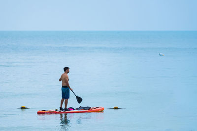 Rear view of shirtless man in sea against sky