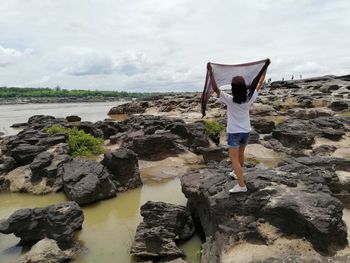 Rear view of woman looking at sea shore against sky