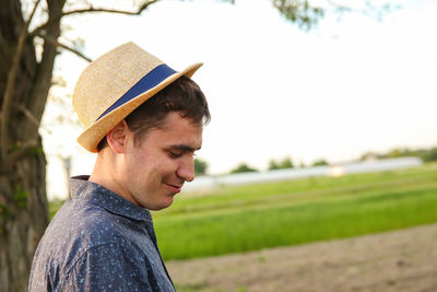 Farmer in hat working on field with greenhouse outdoor. portrait of young caucasian handsome 