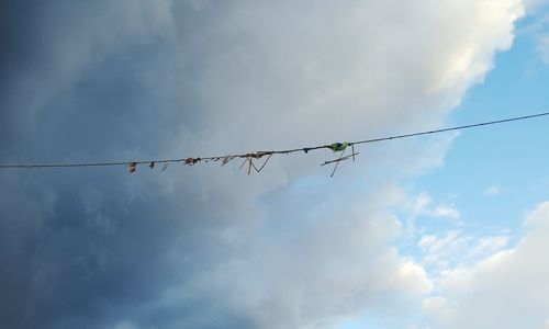 Low angle view of power lines against cloudy sky