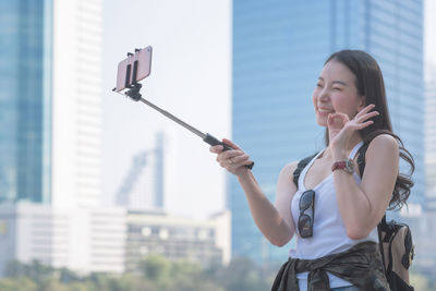 Man photographing with mobile phone standing in city