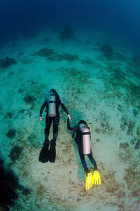 Scuba divers holding hands underwater