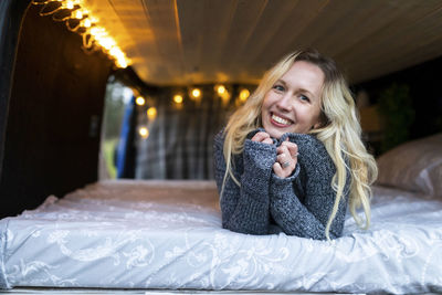 Portrait of a smiling young woman sitting on bed