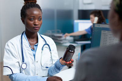 Young doctor showing drug bottle at hospital