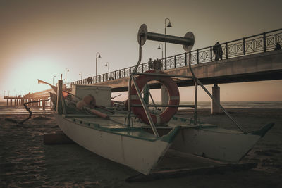 Fishing boat on beach against sky during sunset