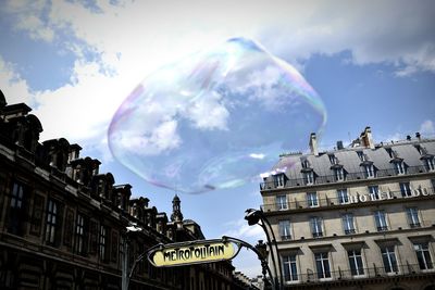 Low angle view of bubble by musee du louvre against cloudy sky