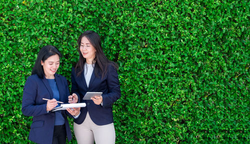 Businesswomen discussing while standing against plants