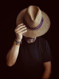 Portrait of man wearing hat against black background