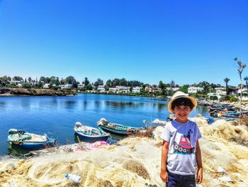 Portrait of boy on shore against clear blue sky