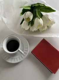 High angle view of coffee on table with journal and flowers