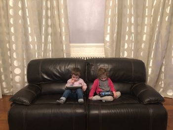 Rear view of children sitting on sofa