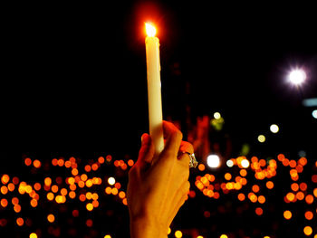 Close-up of hand holding lit candles