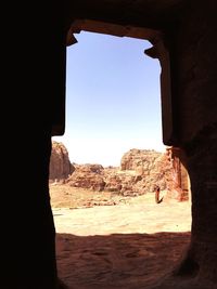 Rock formations against sky seen through entrance at petra